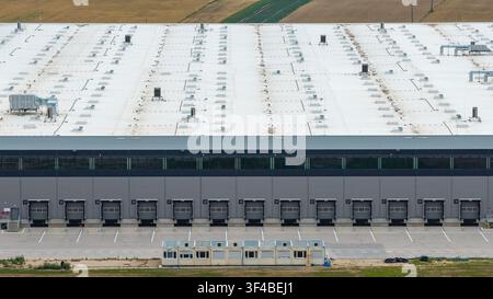 Aerial view of a large warehouse at a distribution center with multiple loading docks and a white roof in Poland. Stock Photo