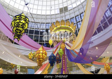 Lanterns in vibrant colors hang from above, surrounded by flowing drapes of various hues. The bright atmosphere showcases a festive setting celebratin Stock Photo