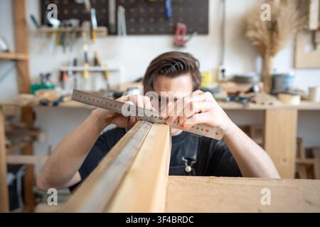 Concentrated craftsman carpenter working on restoration of vintage wooden window frame in workshop. Stock Photo
