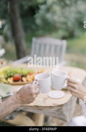 Friends having coffee together. Friends who enjoy breakfast in the midst of a beautiful garden landscape Stock Photo