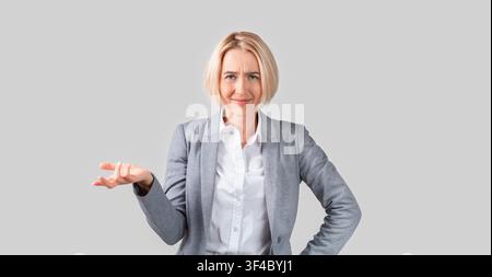 Puzzled mature lady boss asking for explanation on light background Stock Photo