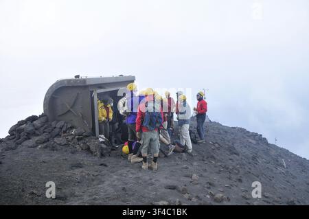 Group of tourists wearing yellow helmets in front of shelter at Stromboli Crater, Stromboli volcanic island, Aeolian or Aeolian Islands, Sicily, South Stock Photo