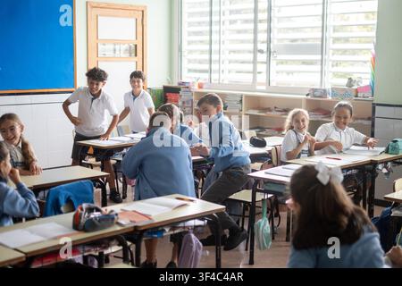 Elementary school girl listening carefully during a classroom lesson while classmates participate. Stock Photo