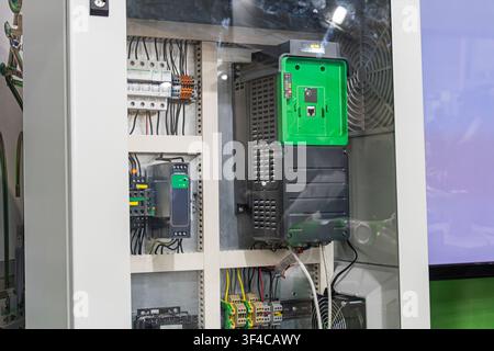 Industrial electrical cabinet featuring a variable frequency drive (VFD) with a green front panel. The enclosure includes circuit breakers, terminal b Stock Photo