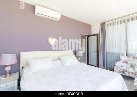 Bright and spacious modern bedroom interior featuring a comfortable double bed Stock Photo