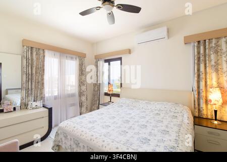 Bright and spacious modern bedroom interior featuring a comfortable double bed Stock Photo