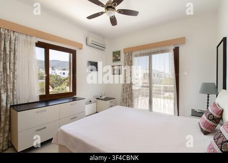 Bright and spacious modern bedroom interior featuring a comfortable double bed Stock Photo
