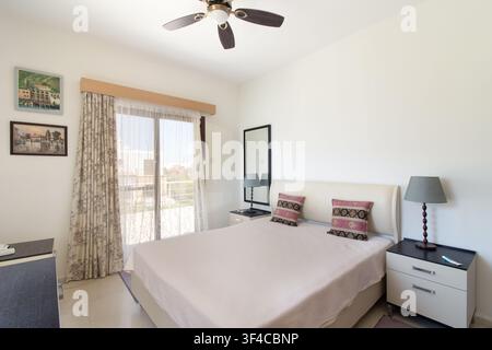 Bright and spacious modern bedroom interior featuring a comfortable double bed Stock Photo