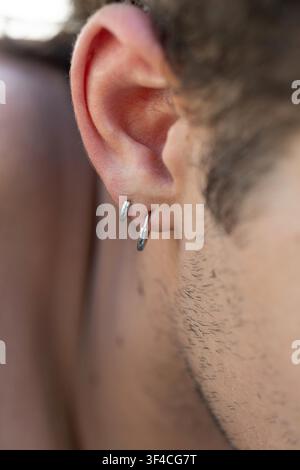 Close-up view of male ear with two modern silver hoop piercings Stock Photo