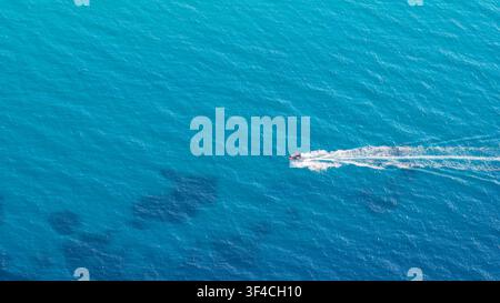 Afytos, Greece 15 July 2025. This aerial photo shows a small motorboat speeding through the bright blue sea waters near Afytos Greece on a sunny day. Stock Photo