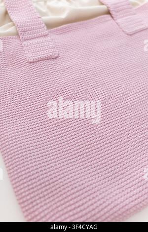 Handcrafted pink knitted tote bag displayed on a neutral background with texture details Stock Photo