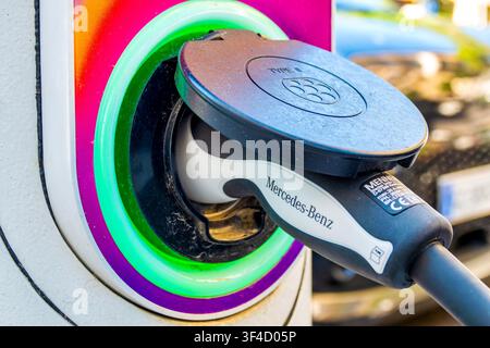 Close up of a Mennekes Type 2 charging plug connected to an electric vehicle port with green indicator light Stock Photo