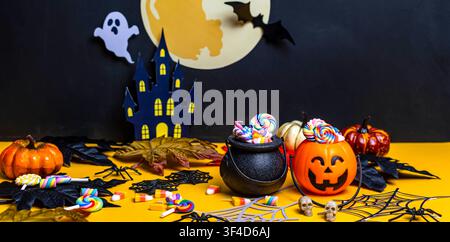Halloween theme decoration with sweets, pumpkins, and a haunted castle on a black and yellow background Stock Photo