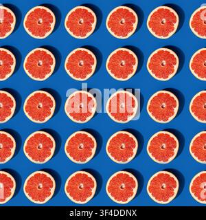 Grapefruit halves arranged in geometric pattern on dark blue background Stock Photo