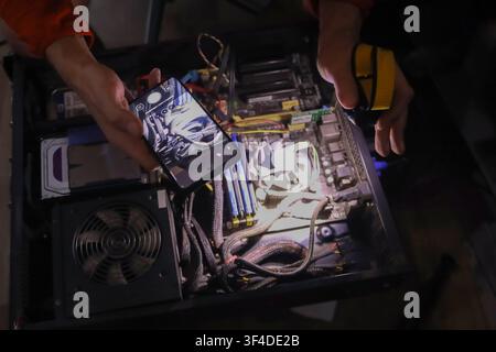 A person holds a smartphone over the internal components of a high performance gaming computer with custom liquid cooling and RGB lighting. Stock Photo