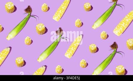 Corn cobs and kernels arranged in playful pattern on purple background Stock Photo