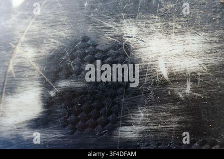 A worn scratched metal surface with black fabric imprint, texture pattern, abrasion marks, distressed finish, industrial feel Stock Photo
