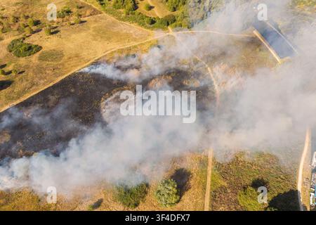 A dramatic aerial photo capturing a wildfire at Rammey Marsh in North London, with thick smoke rising and bright flames burning through dry grassland. Stock Photo