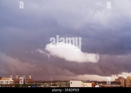 A dramatic and moody cinematic shot of heavy storm clouds gathering across the sky. The natural weather scene displays intense dark gray textures and Stock Photo