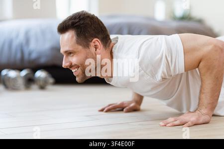 Sporty Man Doing Plank Exercise On Floor Training At Home Stock Photo