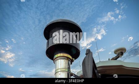 A tractor's exhaust pipe stands tall against a vibrant blue sky dotted with fluffy clouds. The image captures the industrial strength of farming equip Stock Photo