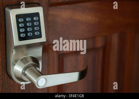 Digital electronic keypad door lock handle mounted on a wooden door Stock Photo