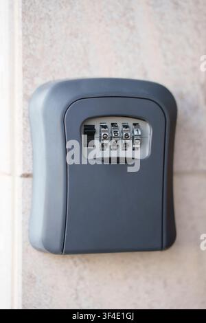 Combination key lock box mounted on a stone wall for safe and secure rental property access Stock Photo