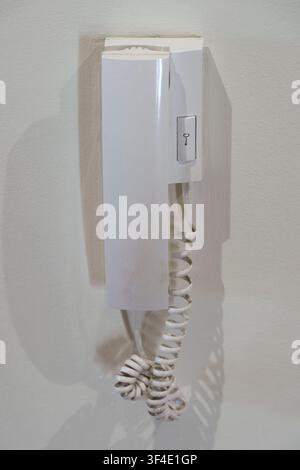 White intercom phone mounted on a wall inside a building interior Stock Photo