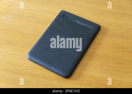 Back view of a Rakuten Kobo Clara BW e-reader lying on a light wooden table surface Stock Photo