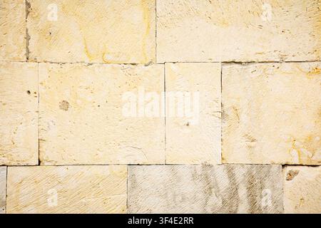 Close-up of pale limestone blocks on a historic building in Georgia forms a warm, minimalist geometric texture with a weathered architectural atmosphe Stock Photo