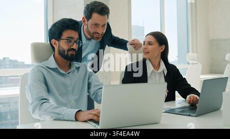 Multiracial business team brainstorming using laptop indoors office happy coworkers discuss project together Arabian businessmen businesswoman Stock Photo