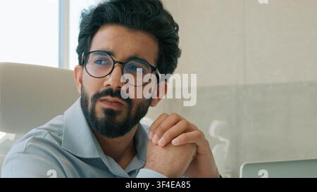 Thoughtful pensive Arabian businessman Indian man entrepreneur working computer in office analyzing online business project thinking solving problem Stock Photo