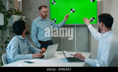 Man CEO talking to multiracial business team presentation at office conference meeting businessmen males workers listening discussing design analysis Stock Photo