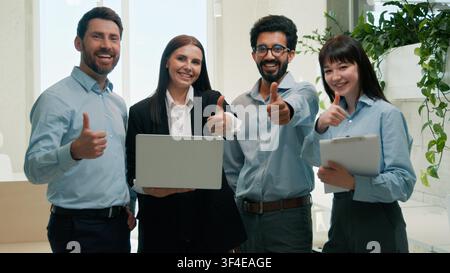 Diverse business team discussing project CEO in office thumbs up approval men woman using laptop teamwork corporate staff multiracial employees good Stock Photo