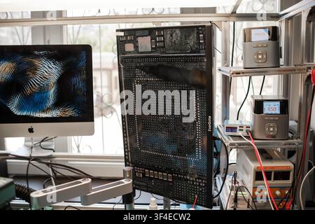Moscow, Russia - July 02, 2026: Computer workstation with circuit board, monitor displaying digital patterns, and electronic testing equipment in Stock Photo