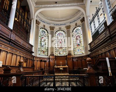 Manchester, UK - May 10, 2026: Ornate historic St Ann's church interior with carved wood panelling, colorful stained glass windows and central altar. Stock Photo