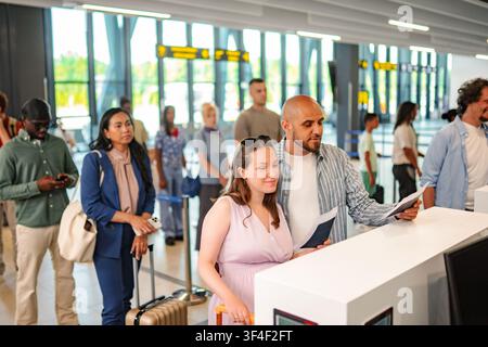 Diverse group of people checking in at airport counter Stock Photo
