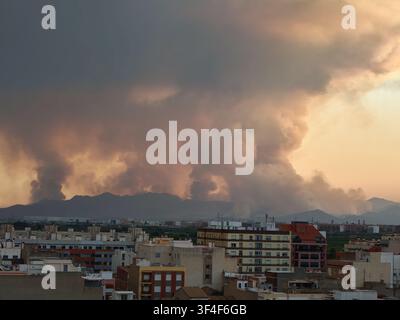Thick smoke from a large wildfire billows across the sky over urban buildings in almassora, valencian community, demonstrating the serious impact of n Stock Photo