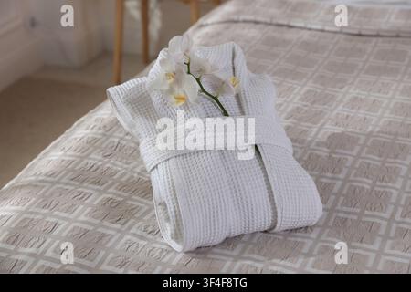 Clean bathrobe with flowers on bed indoors, closeup Stock Photo
