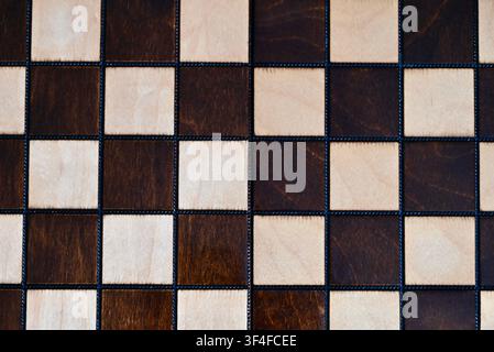 A clean, top-down flat lay photograph of an empty wooden chessboard showing alternating light and dark squares with natural wood grain texture. The minimalistic pattern serves as a versatile background or template for strategic concepts, business planning, decision-making framework, game design, and intellectual themes. Perfect space for placing custom text or objects. Stock Photo