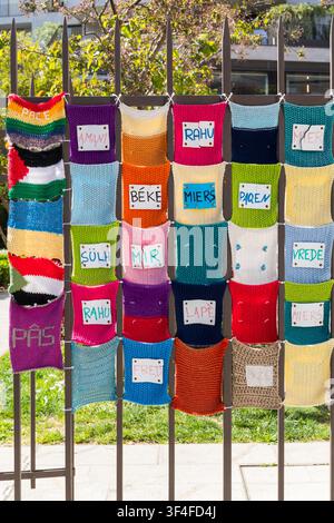 A colorful display of knitted and crocheted flags with a labels sewn onto them. Labels contain word peace in different languages. Stock Photo