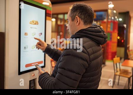 Man using a touchscreen ordering kiosk in a fast food restaurant Stock Photo