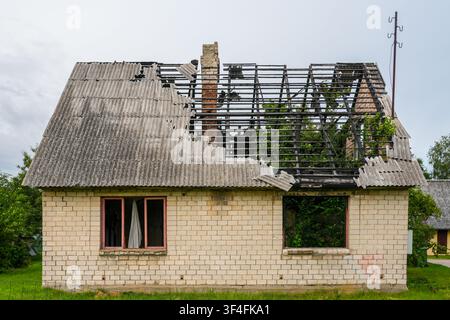 Abandoned Fire Damaged Brick House with Destroyed Roof Structure and Severe Structural Decay Exterior Stock Photo