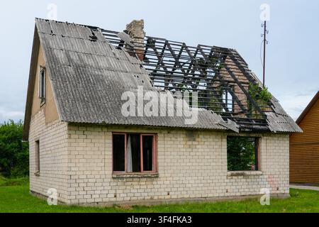 Fire Damaged Abandoned Brick House with Collapsed Roof Structure and Severe Structural Damage Exterior Stock Photo