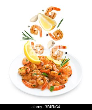 Tasty grilled shrimps, lemon slices, garlic cloves, rosemary and peppercorns falling on white background Stock Photo