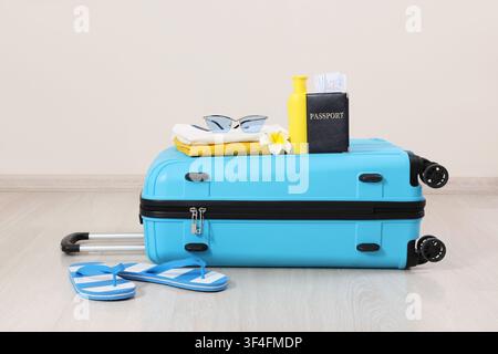 Blue travel suitcase with passport, tickets, sunglasses, and flip-flops for summer vacation planning Stock Photo