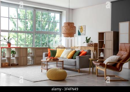 Comfortable sofa, armchair and tray with apricots on coffee table in interior of living room Stock Photo