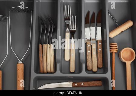Kitchen drawer organizer with various wooden handle cutlery and cooking utensils, top down view Stock Photo