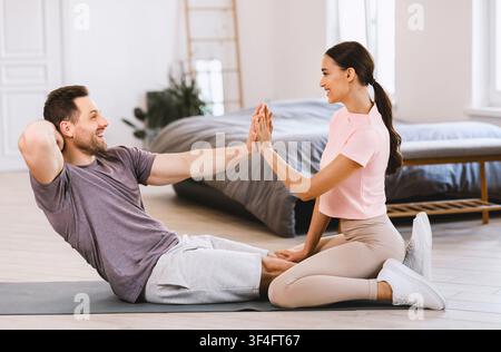 Sporty Couple Training Together Doing Abs Exercise At Home Stock Photo