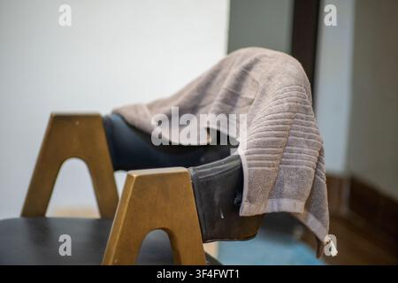 Brown towel draped over black chair in room Stock Photo